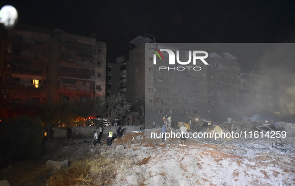 People watch as a blaze rages amid the smoldering rubble of a building destroyed in an Israeli air strike in the Haret Hreik neighborhood of...