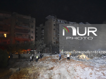 People watch as a blaze rages amid the smoldering rubble of a building destroyed in an Israeli air strike in the Haret Hreik neighborhood of...