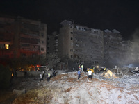 People watch as a blaze rages amid the smoldering rubble of a building destroyed in an Israeli air strike in the Haret Hreik neighborhood of...