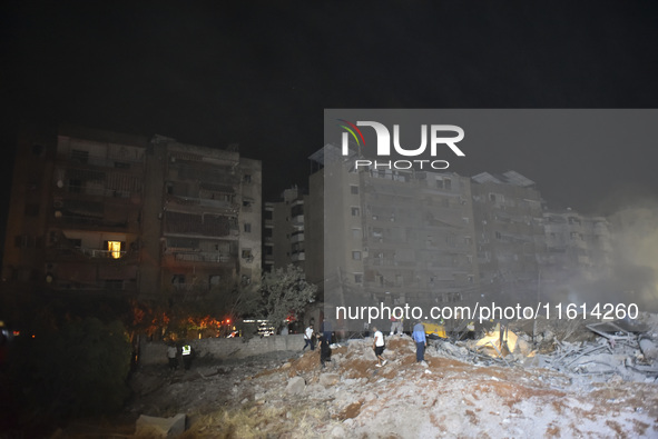 People watch as a blaze rages amid the smoldering rubble of a building destroyed in an Israeli air strike in the Haret Hreik neighborhood of...