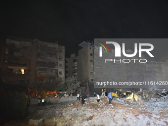 People watch as a blaze rages amid the smoldering rubble of a building destroyed in an Israeli air strike in the Haret Hreik neighborhood of...