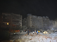 People watch as a blaze rages amid the smoldering rubble of a building destroyed in an Israeli air strike in the Haret Hreik neighborhood of...