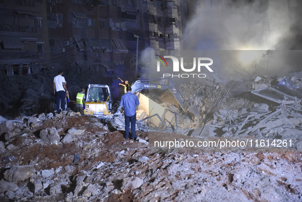 People watch as a blaze rages amid the smoldering rubble of a building destroyed in an Israeli air strike in the Haret Hreik neighborhood of...