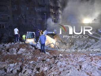 People watch as a blaze rages amid the smoldering rubble of a building destroyed in an Israeli air strike in the Haret Hreik neighborhood of...