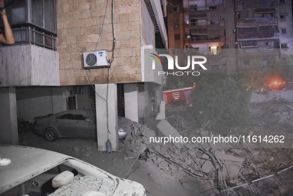 People watch as a blaze rages amid the smoldering rubble of a building destroyed in an Israeli air strike in the Haret Hreik neighborhood of...