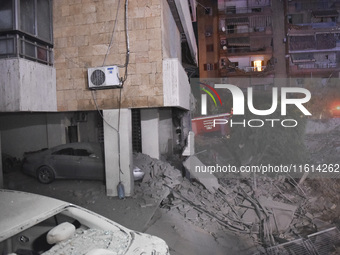 People watch as a blaze rages amid the smoldering rubble of a building destroyed in an Israeli air strike in the Haret Hreik neighborhood of...