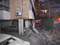 People watch as a blaze rages amid the smoldering rubble of a building destroyed in an Israeli air strike in the Haret Hreik neighborhood of...