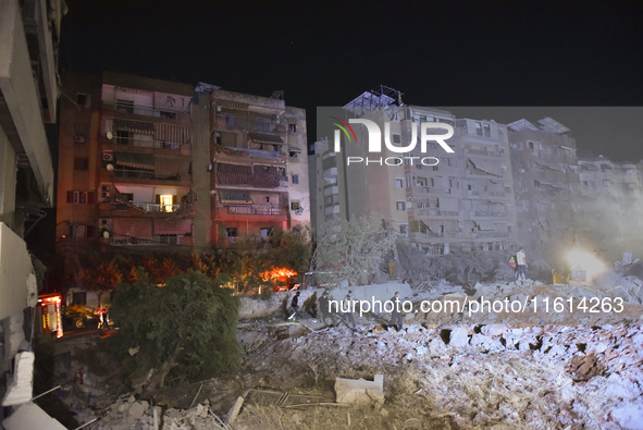 People watch as a blaze rages amid the smoldering rubble of a building destroyed in an Israeli air strike in the Haret Hreik neighborhood of...