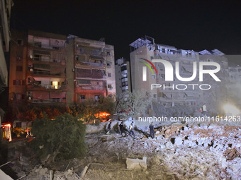 People watch as a blaze rages amid the smoldering rubble of a building destroyed in an Israeli air strike in the Haret Hreik neighborhood of...