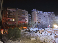 People watch as a blaze rages amid the smoldering rubble of a building destroyed in an Israeli air strike in the Haret Hreik neighborhood of...