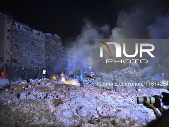 People watch as a blaze rages amid the smoldering rubble of a building destroyed in an Israeli air strike in the Haret Hreik neighborhood of...