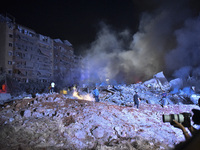 People watch as a blaze rages amid the smoldering rubble of a building destroyed in an Israeli air strike in the Haret Hreik neighborhood of...