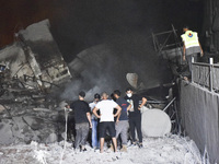 People watch as a blaze rages amid the smoldering rubble of a building destroyed in an Israeli air strike in the Haret Hreik neighborhood of...