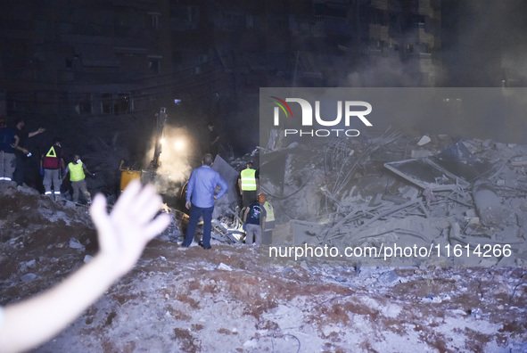 People watch as a blaze rages amid the smoldering rubble of a building destroyed in an Israeli air strike in the Haret Hreik neighborhood of...