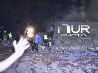 People watch as a blaze rages amid the smoldering rubble of a building destroyed in an Israeli air strike in the Haret Hreik neighborhood of...