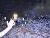 People watch as a blaze rages amid the smoldering rubble of a building destroyed in an Israeli air strike in the Haret Hreik neighborhood of...