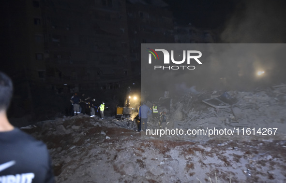 People watch as a blaze rages amid the smoldering rubble of a building destroyed in an Israeli air strike in the Haret Hreik neighborhood of...