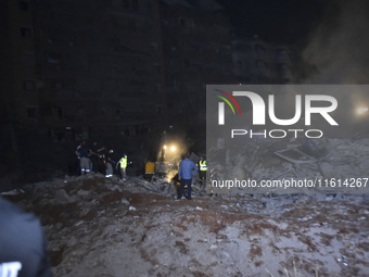 People watch as a blaze rages amid the smoldering rubble of a building destroyed in an Israeli air strike in the Haret Hreik neighborhood of...