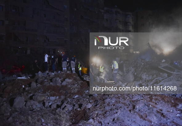 People watch as a blaze rages amid the smoldering rubble of a building destroyed in an Israeli air strike in the Haret Hreik neighborhood of...