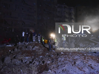 People watch as a blaze rages amid the smoldering rubble of a building destroyed in an Israeli air strike in the Haret Hreik neighborhood of...