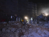 People watch as a blaze rages amid the smoldering rubble of a building destroyed in an Israeli air strike in the Haret Hreik neighborhood of...