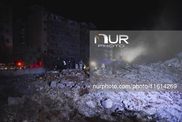 People watch as a blaze rages amid the smoldering rubble of a building destroyed in an Israeli air strike in the Haret Hreik neighborhood of...