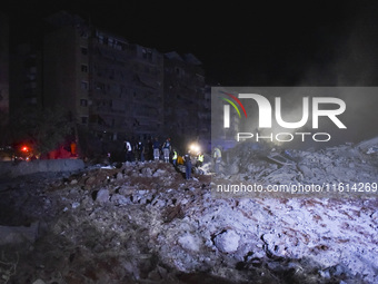 People watch as a blaze rages amid the smoldering rubble of a building destroyed in an Israeli air strike in the Haret Hreik neighborhood of...