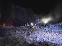 People watch as a blaze rages amid the smoldering rubble of a building destroyed in an Israeli air strike in the Haret Hreik neighborhood of...