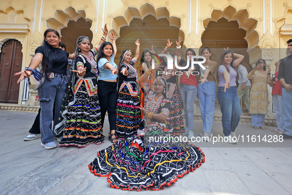 Rajasthani folk artists pose for a photo with tourists during the World Tourism Day celebration at the historical Hawa Mahal in Jaipur, Raja...