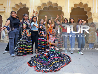 Rajasthani folk artists pose for a photo with tourists during the World Tourism Day celebration at the historical Hawa Mahal in Jaipur, Raja...