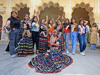 Rajasthani folk artists pose for a photo with tourists during the World Tourism Day celebration at the historical Hawa Mahal in Jaipur, Raja...