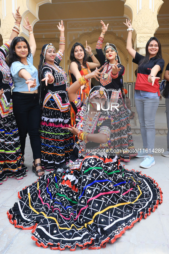 Rajasthani folk artists pose for a photo with tourists during the World Tourism Day celebration at the historical Hawa Mahal in Jaipur, Raja...