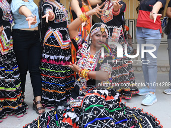 Rajasthani folk artists pose for a photo with tourists during the World Tourism Day celebration at the historical Hawa Mahal in Jaipur, Raja...