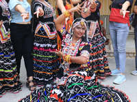 Rajasthani folk artists pose for a photo with tourists during the World Tourism Day celebration at the historical Hawa Mahal in Jaipur, Raja...