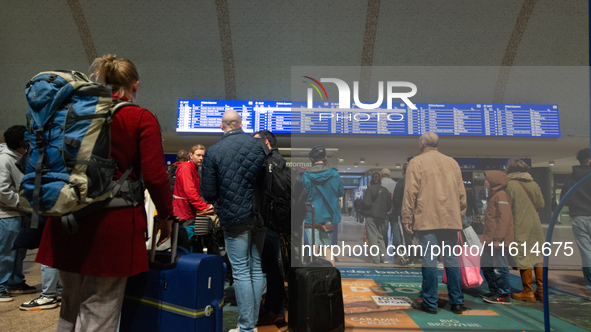 Travelers wait in line in front of the train information desk at Cologne Central Station due to construction work. Cologne Central Station c...