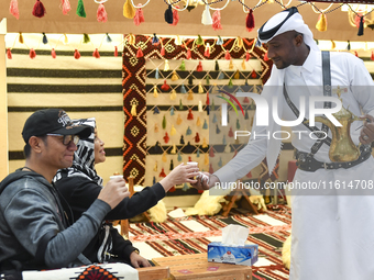 A Qatari man serves traditional Arabic coffee to visitors during the 2024 Doha International Coffee Exhibition at Doha Exhibition and Conven...