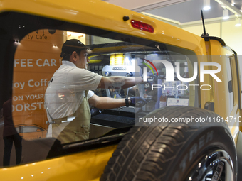 An exhibitor operates a new coffee maker at a mobile vehicle coffee booth during the 2024 Doha International Coffee Exhibition at Doha Exhib...