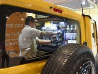 An exhibitor operates a new coffee maker at a mobile vehicle coffee booth during the 2024 Doha International Coffee Exhibition at Doha Exhib...