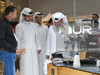 Visitors look at the coffee maker at a booth during the 2024 Doha International Coffee Exhibition at Doha Exhibition and Convention Center i...