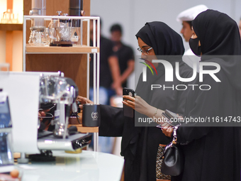 Visitors watch coffee products at a booth during the 2024 Doha International Coffee Exhibition at Doha Exhibition and Convention Center in D...