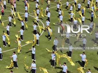 Students dance with a colored ribbon dragon at the No. 2 Middle School of Ecological Cultural Tourism District in Huai'an, China, on Septemb...