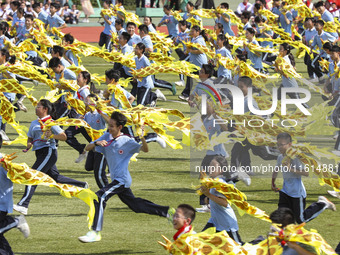 Students dance with a colored ribbon dragon at the No. 2 Middle School of Ecological Cultural Tourism District in Huai'an, China, on Septemb...