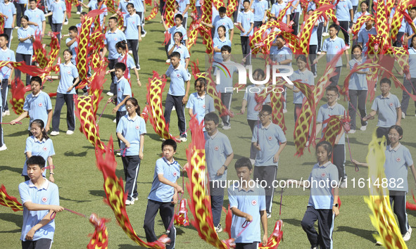 Students dance with a colored ribbon dragon at the No. 2 Middle School of Ecological Cultural Tourism District in Huai'an, China, on Septemb...