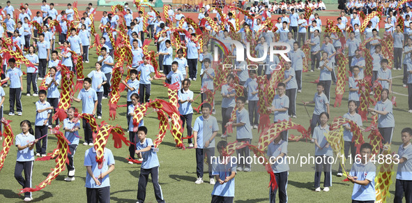 Students dance with a colored ribbon dragon at the No. 2 Middle School of Ecological Cultural Tourism District in Huai'an, China, on Septemb...