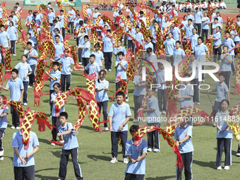 Students dance with a colored ribbon dragon at the No. 2 Middle School of Ecological Cultural Tourism District in Huai'an, China, on Septemb...