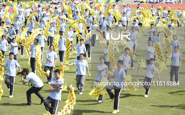 Students dance with a colored ribbon dragon at the No. 2 Middle School of Ecological Cultural Tourism District in Huai'an, China, on Septemb...