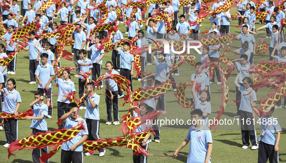 Students dance with a colored ribbon dragon at the No. 2 Middle School of Ecological Cultural Tourism District in Huai'an, China, on Septemb...