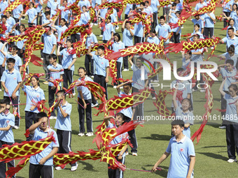 Students dance with a colored ribbon dragon at the No. 2 Middle School of Ecological Cultural Tourism District in Huai'an, China, on Septemb...