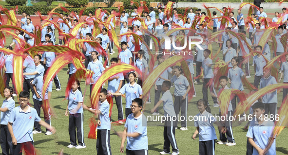 Students dance with a colored ribbon dragon at the No. 2 Middle School of Ecological Cultural Tourism District in Huai'an, China, on Septemb...