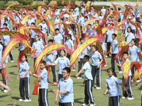 Students dance with a colored ribbon dragon at the No. 2 Middle School of Ecological Cultural Tourism District in Huai'an, China, on Septemb...